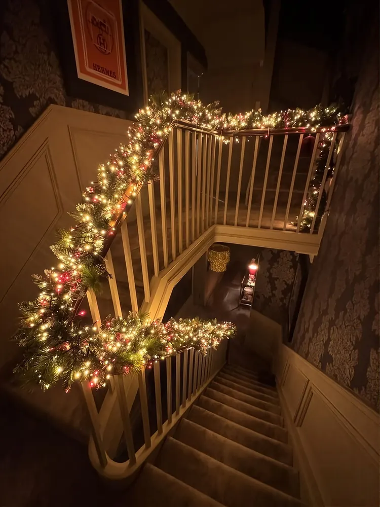 Staircase railing wrapped in lit garland