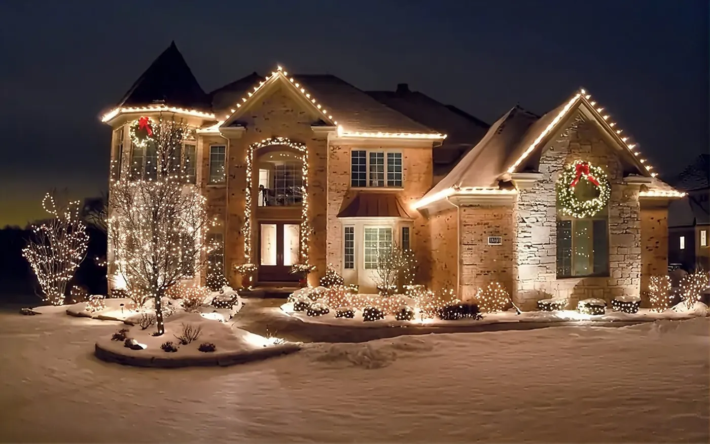 Two-storey house with warm white roofline lights in the snow