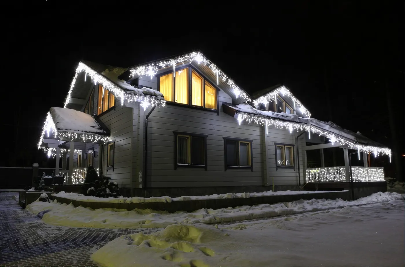 House with white icicle lights along every roofline and porch railing